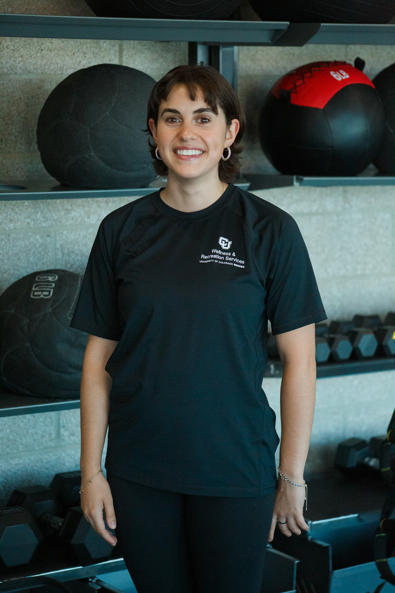 Phoebe the fitness instructor standing and smiling at the gym