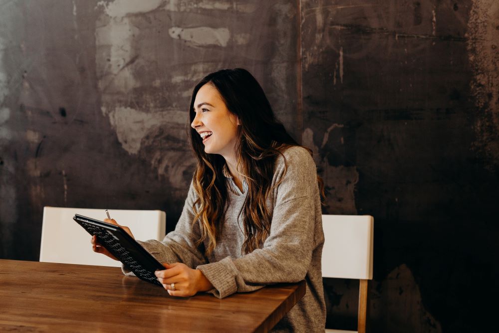 Woman smiling while holding a tablet