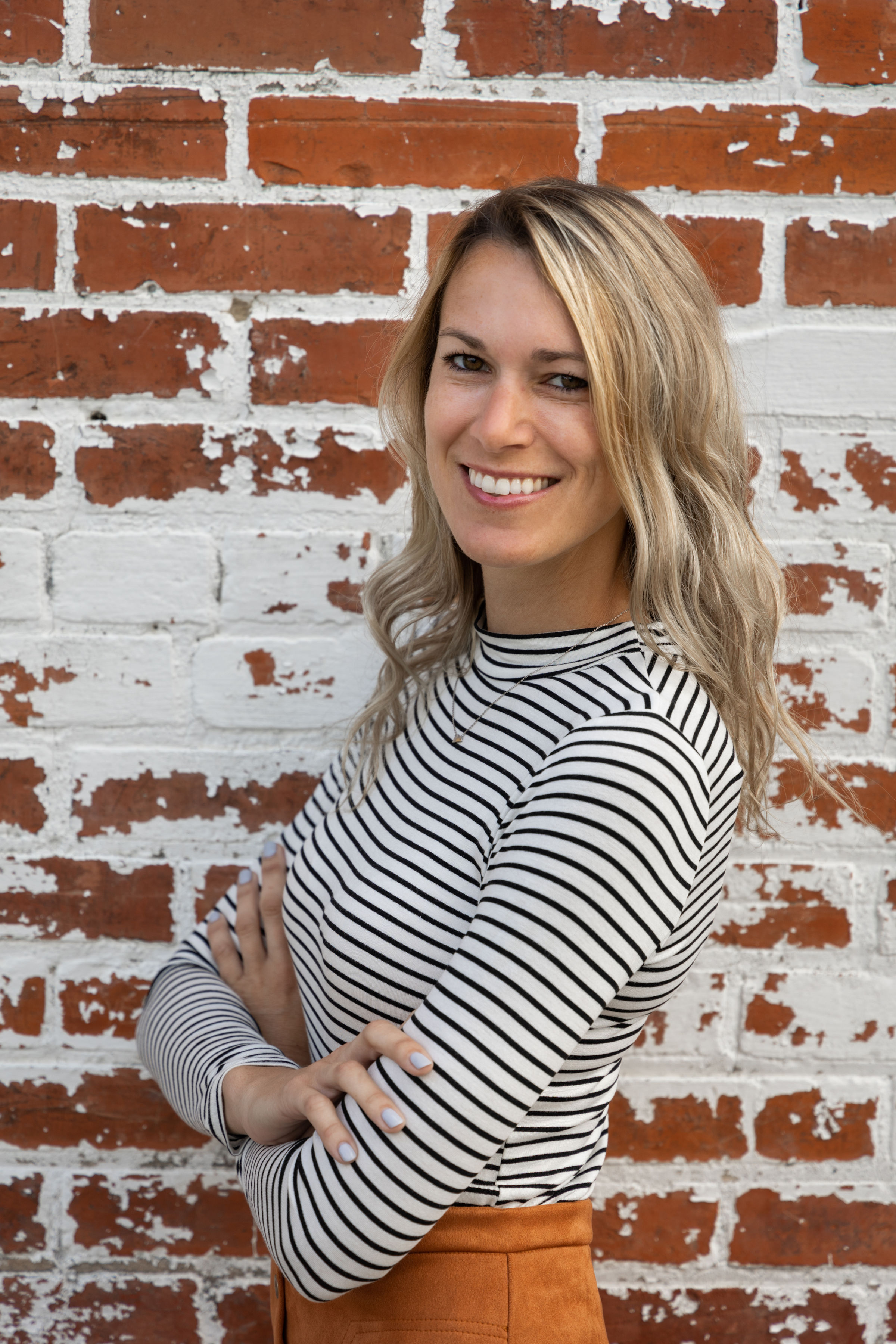 Amy Linville smiling in front of a brick wall