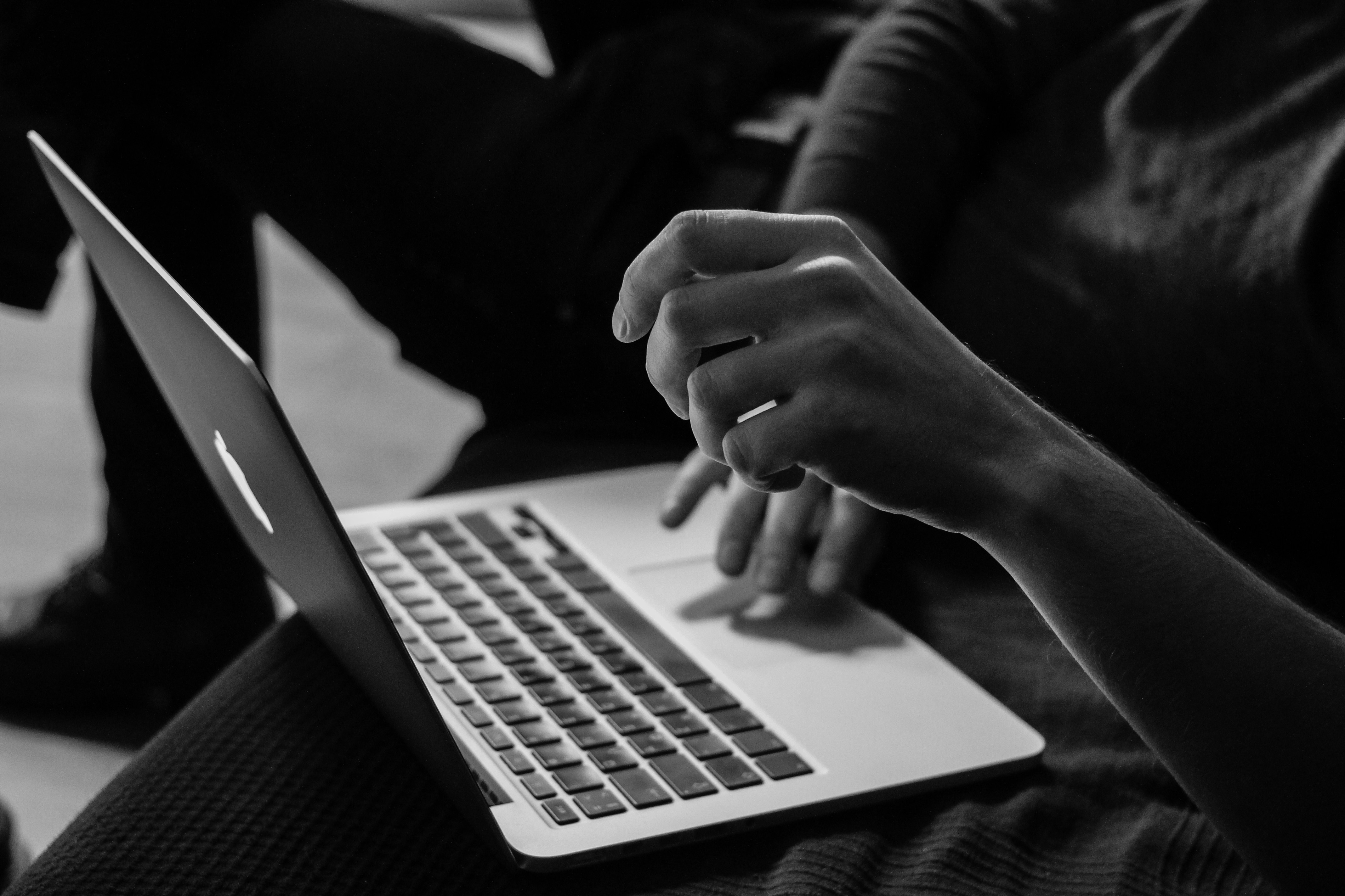 Hands working on a laptop in black and white