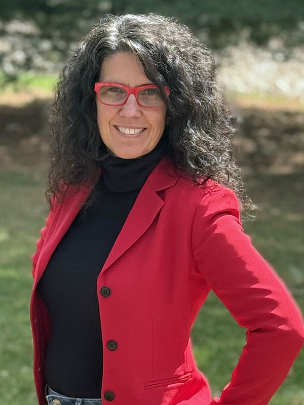 image of a woman with glasses and red blazer posing for a photo, smiling