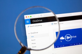 magnifying glass hovering over Microsoft OneDrive logo on a laptop screen