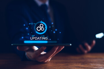 Image of a software update (shown via gears and progress bar) happening on an ipad, behind held by a person's hands.