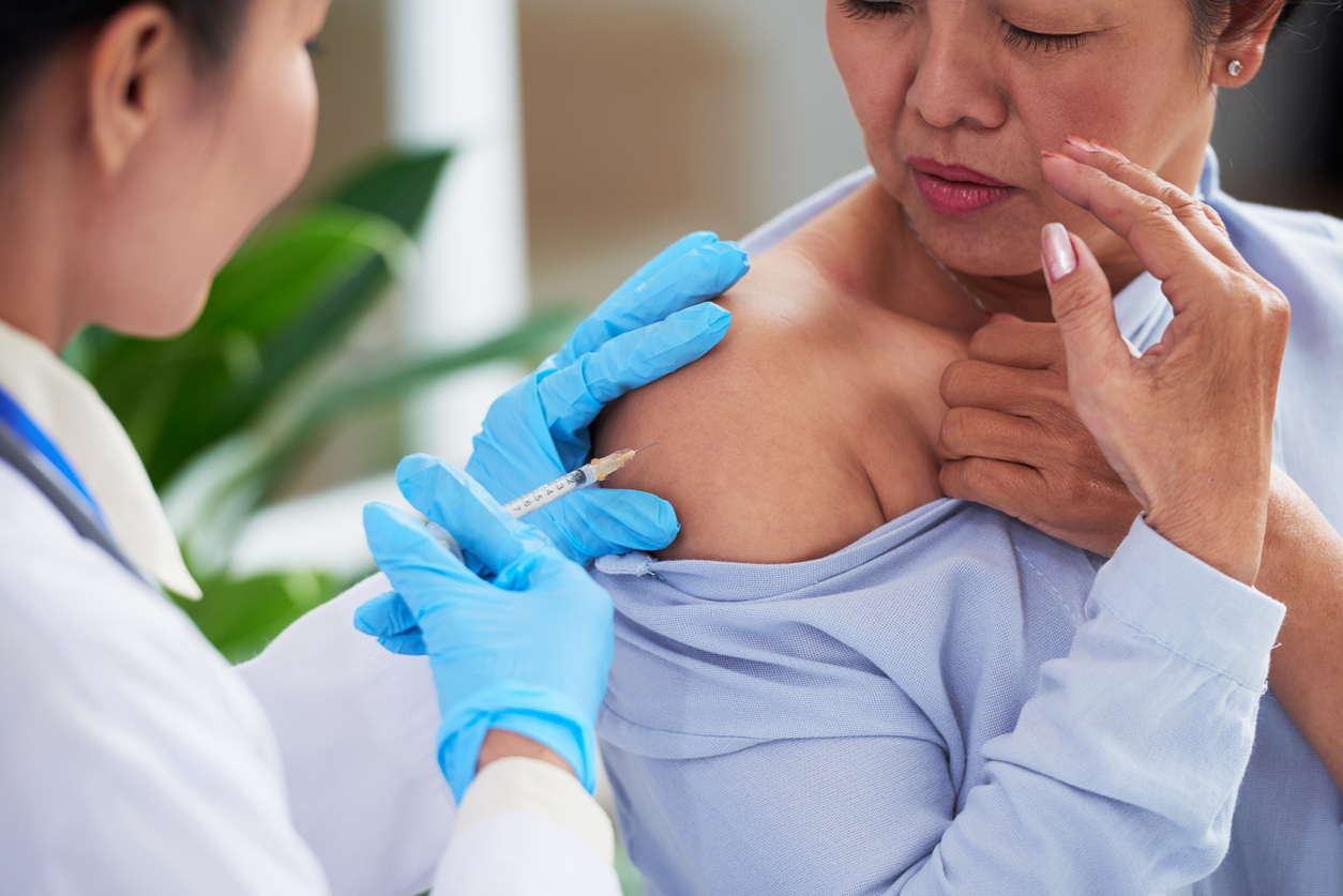 Elderly Asian woman receiving injection from nurse