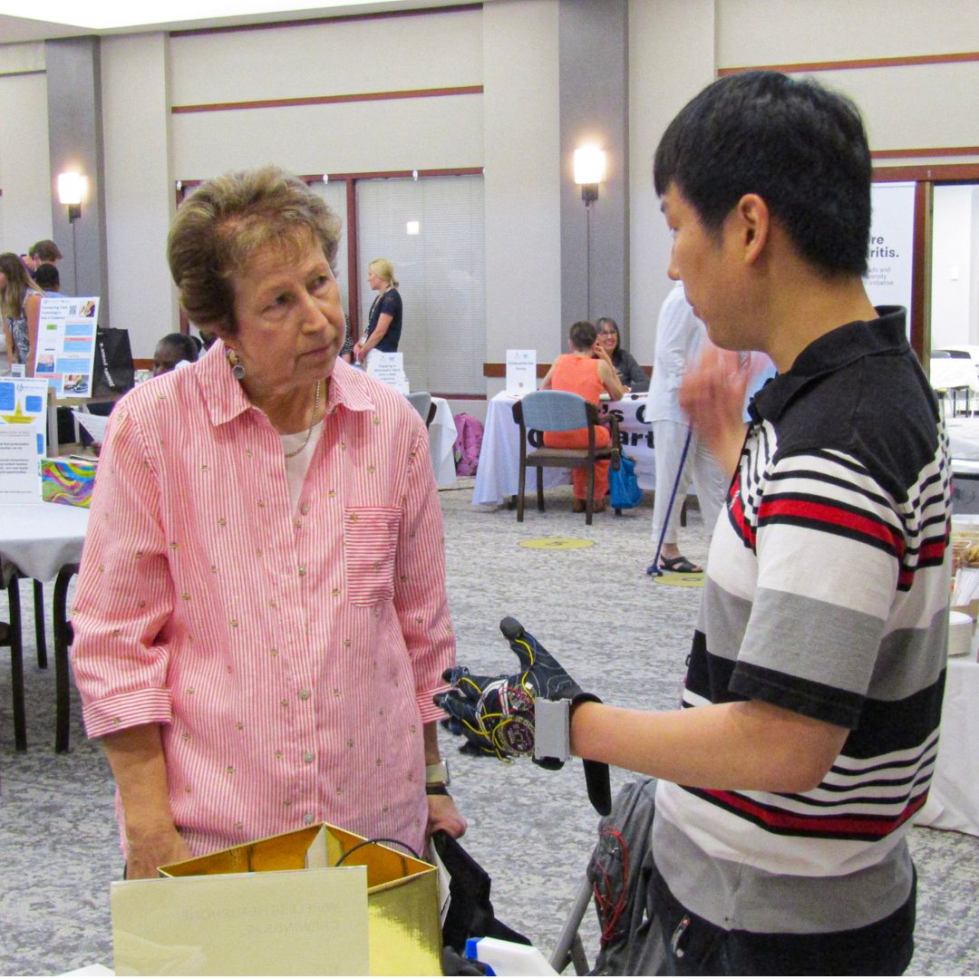 Participant speaking with a researcher demonstrating a glove designed to help treat Alzheimer's.