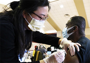 masked doctor giving vaccine to masked man