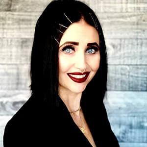 Woman with long black hair and red lipstick smiles with her teeth.
