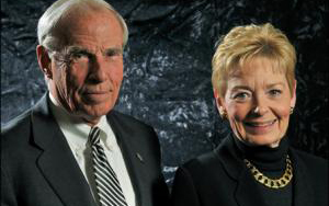 A man and woman posed in a portrait wearing business professional attire and smiling.
