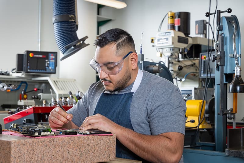 Man in safety goggles doing focused work in a lab.