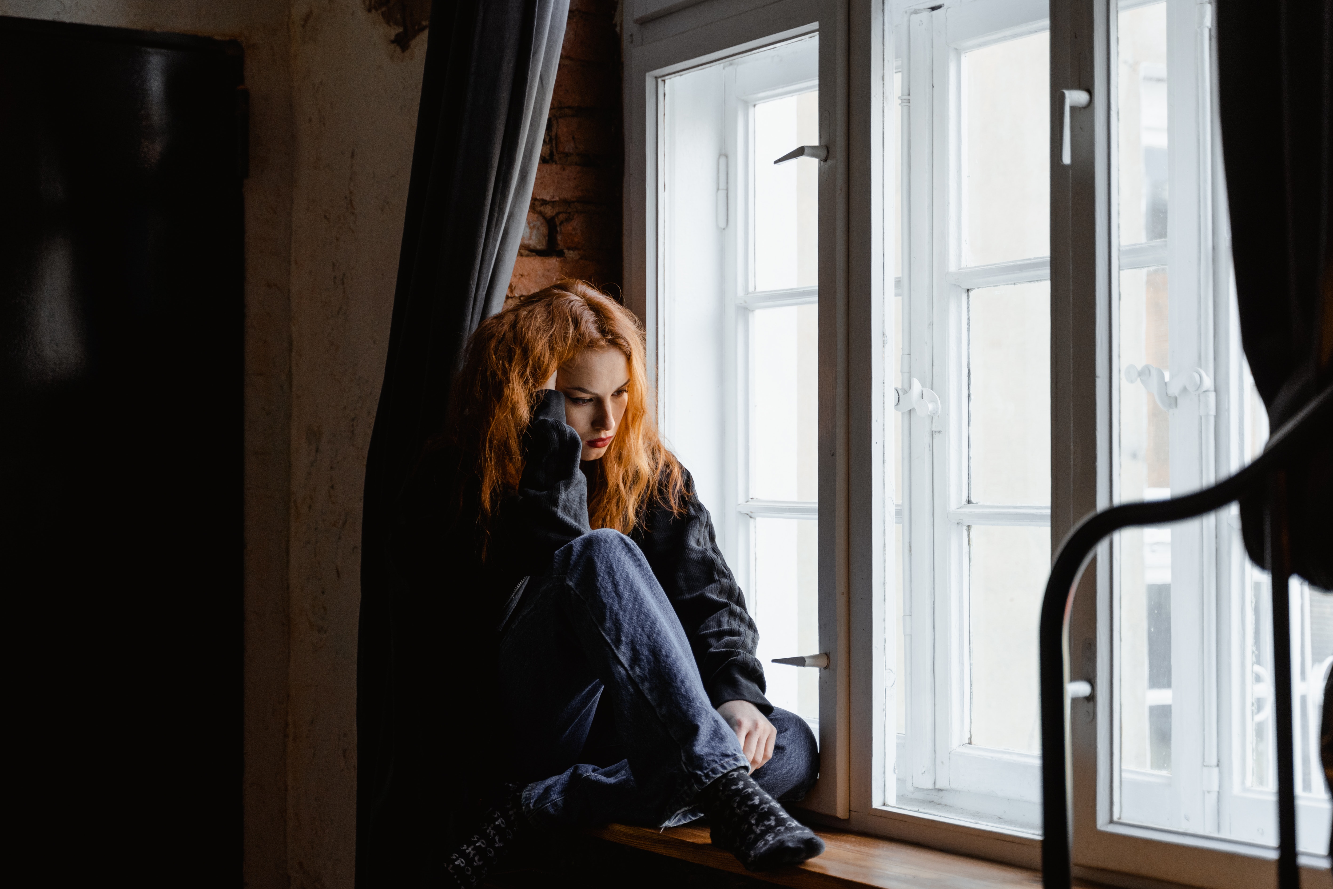 Girl sitting in dark window