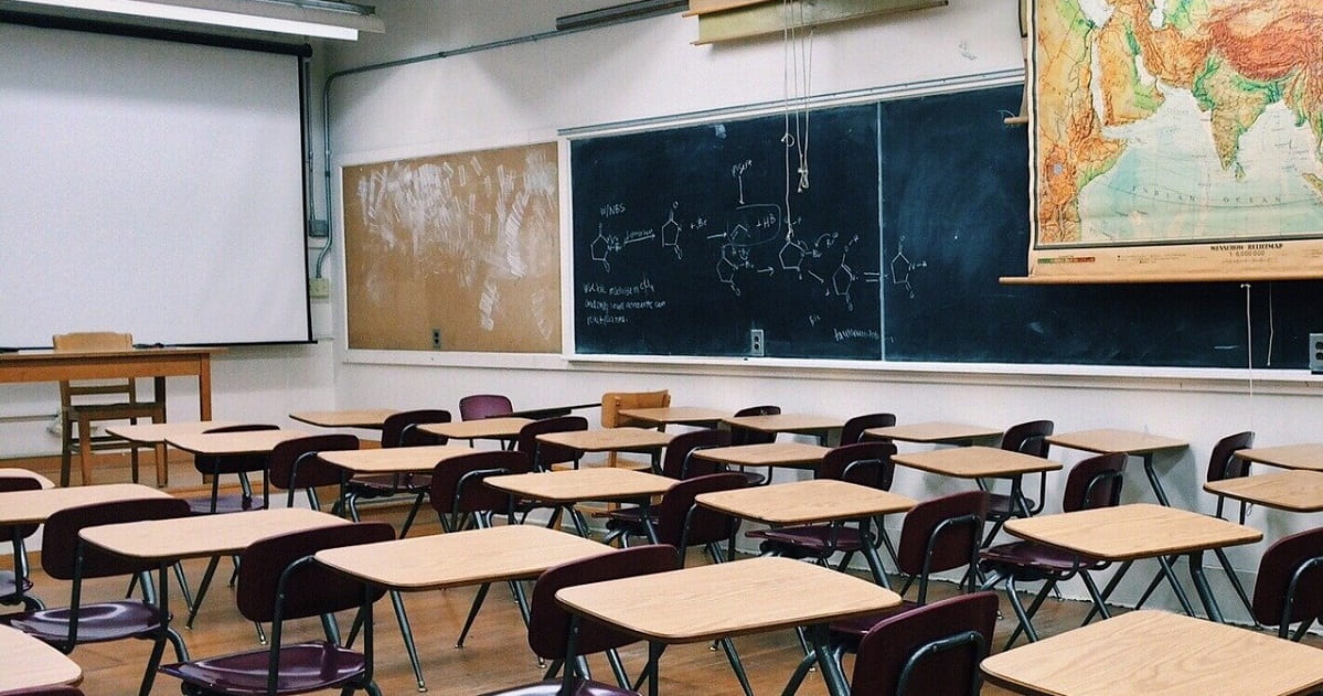 Desks and chalkboard in empty classroom