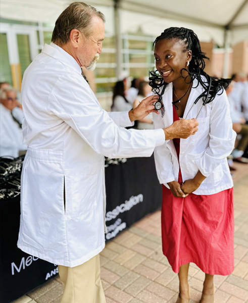 A first year student receiving her stethoscope from a faculty member during the 2024 matriculation ceremony.