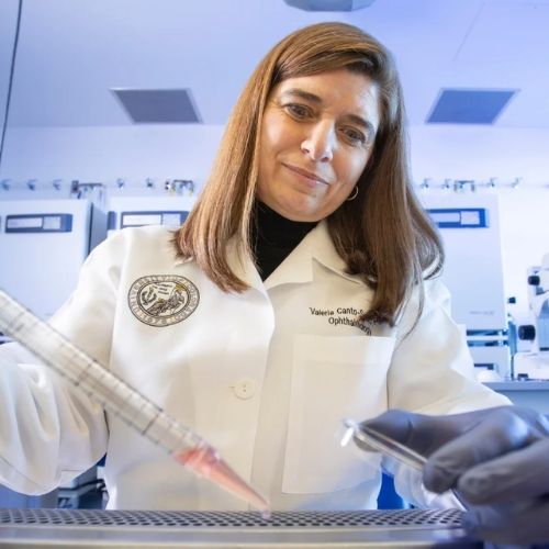 Ophthalmology researcher wearing white lab coat conducts an experiment using a dropper.