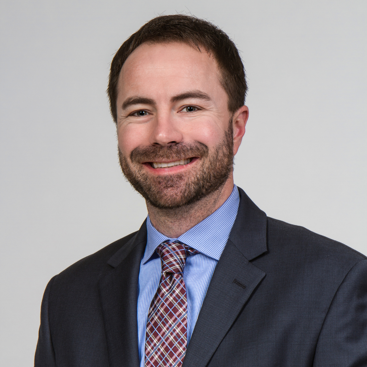Doctor with checkered tie and beard smiling