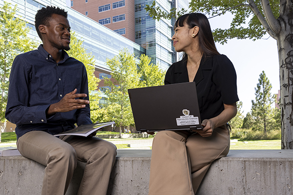 Two students sitting on concrete bench talking