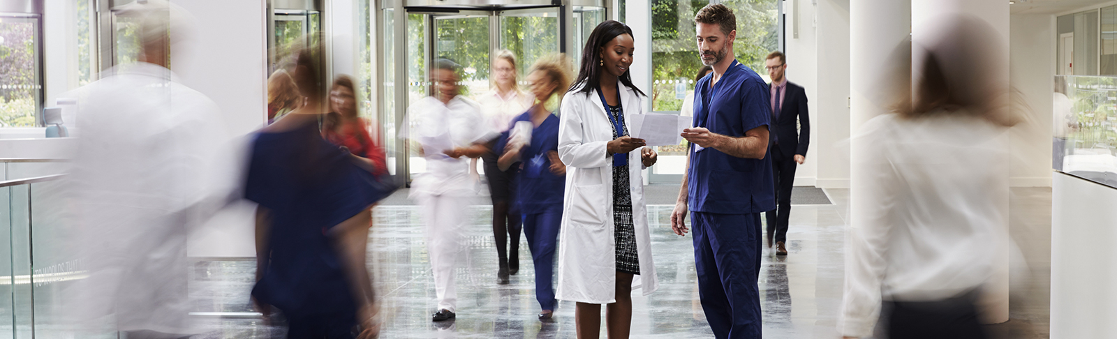 Doctors in clinic lobby, They are in focus, but everyone else is blurred. Doors in background