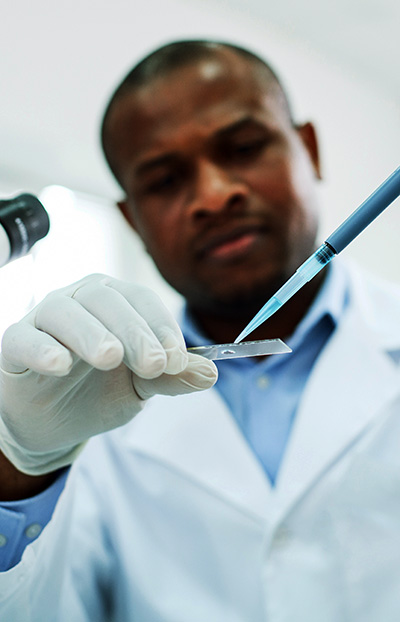 researcher in white coat with syringe and a glass plate