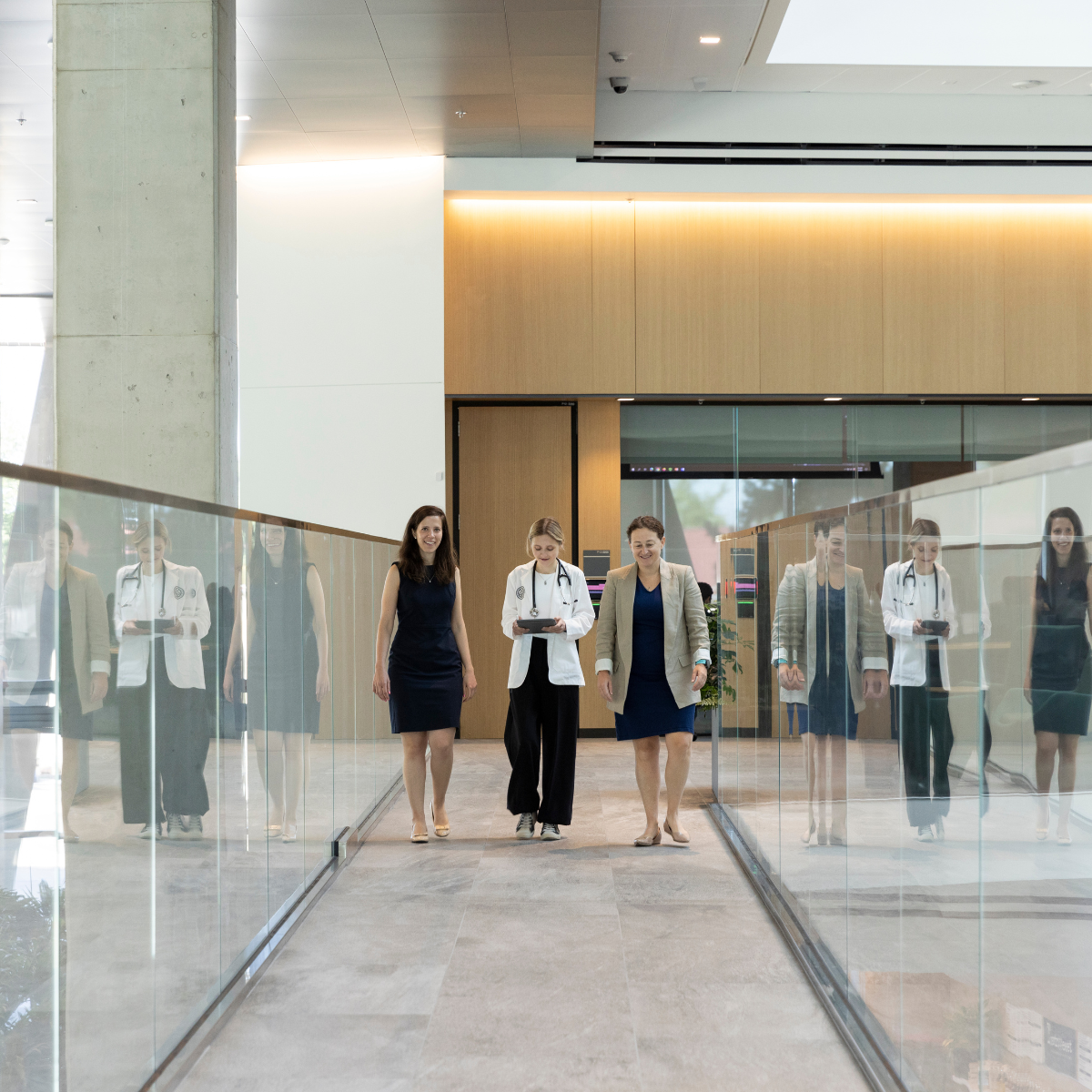 women walk in glass hallway