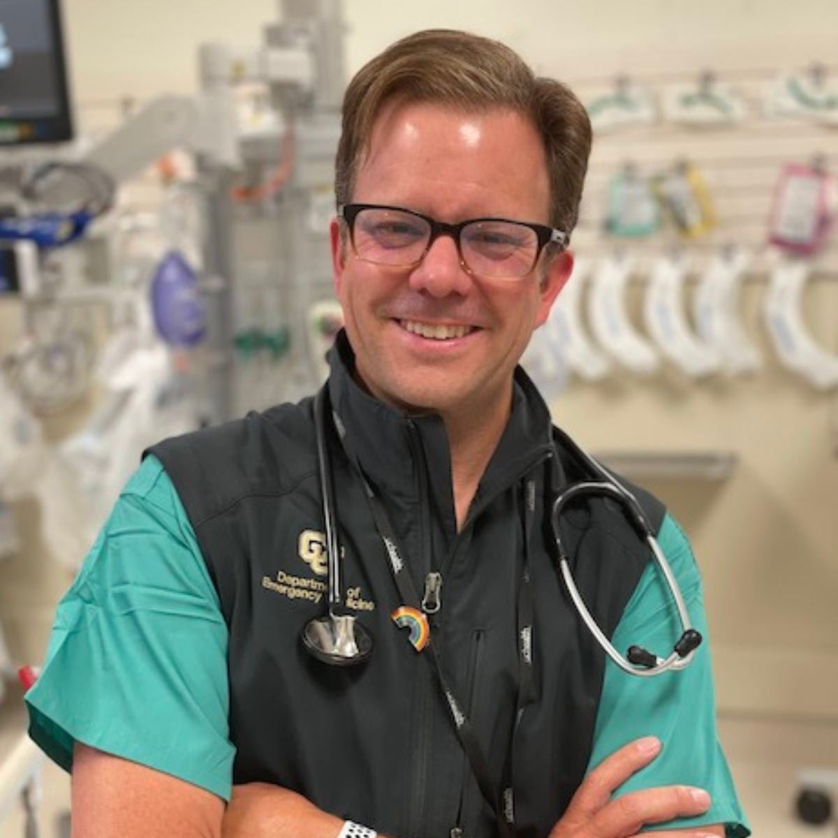 Doctor in scrubs and CU vest with stethoscope smiling