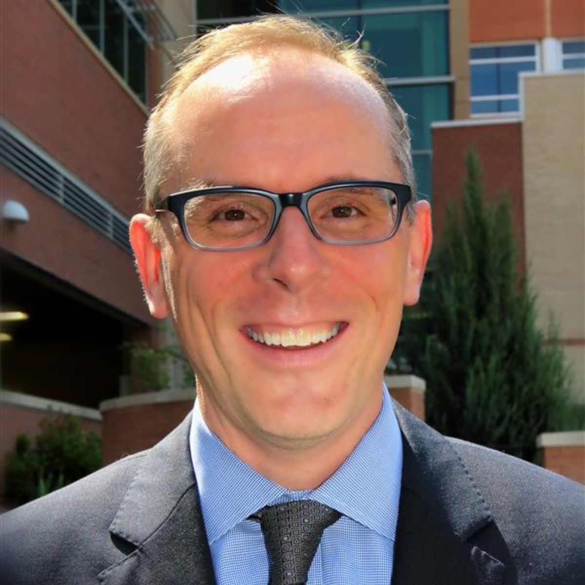 Man with glasses and suit smiling