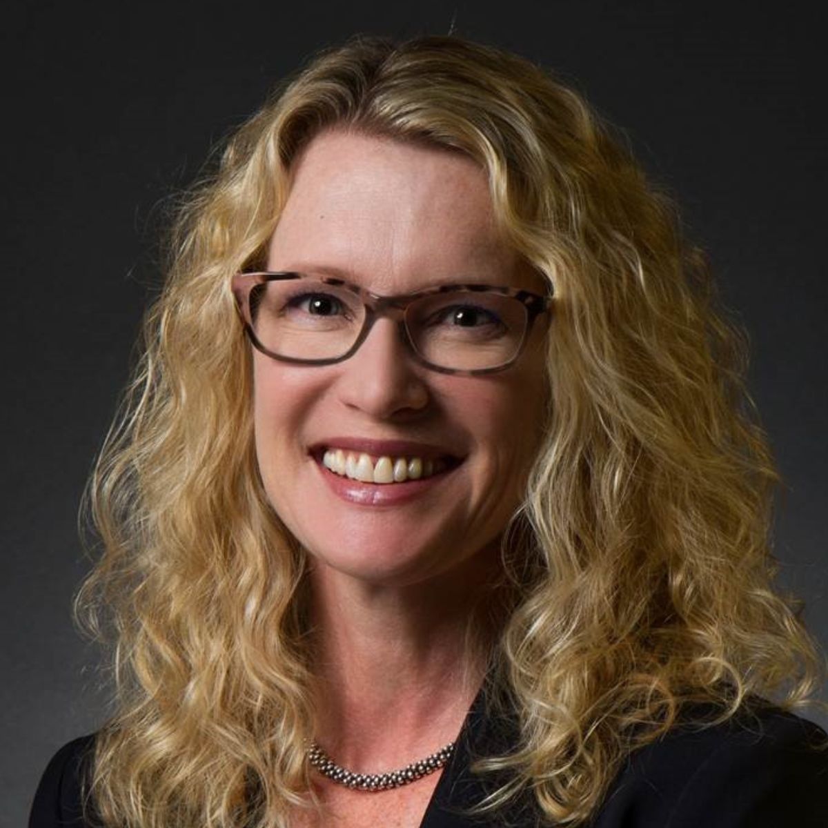 woman with curly hair and black suit jacket
