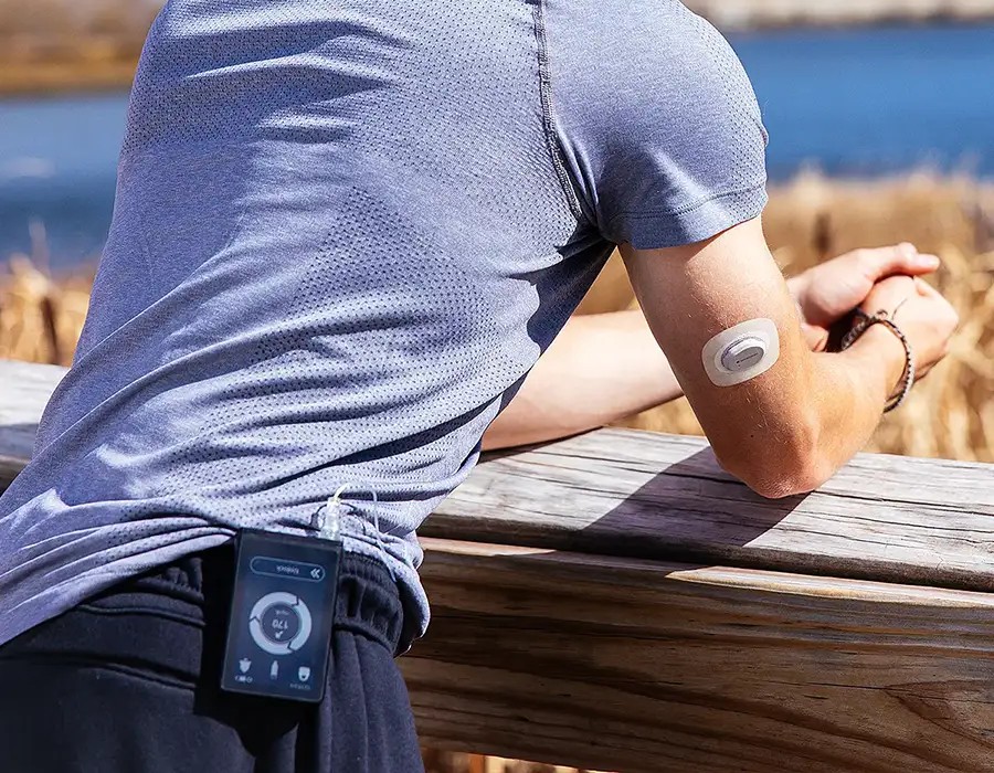 A person standing outside, wearing the iLet bionic pancreas delivery system
