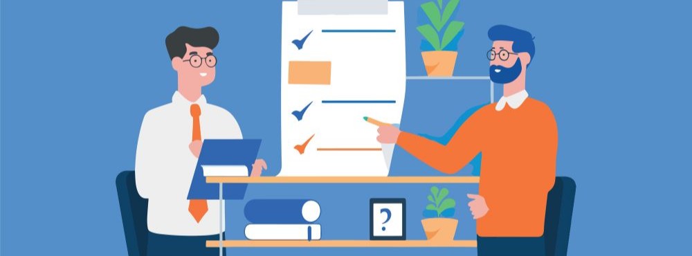 Two professionals are discussing a checklist on a wall, with potted plants and a shelf of books in the background.