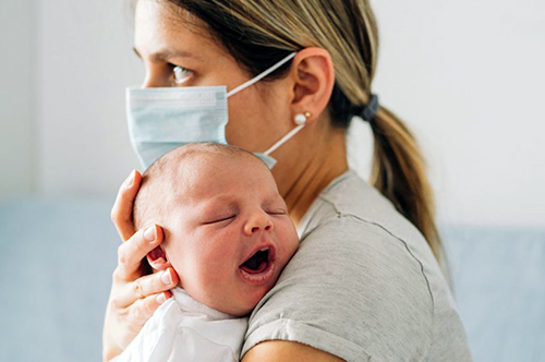 woman wearing mask holding baby