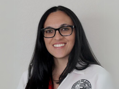 Woman with long black hair in a lab coat and glasses
