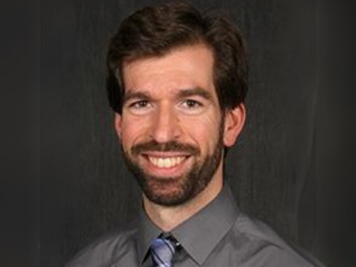 Man in grey button up shirt with a beard