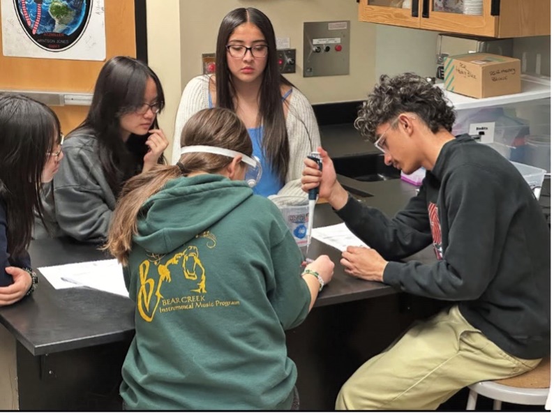 group of 5 high school students doing a lab experiment