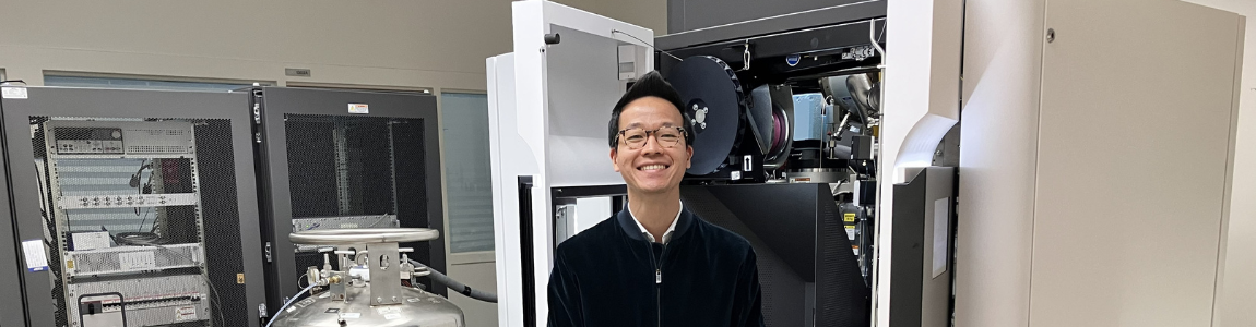 Man standing in front of a large microscope machine