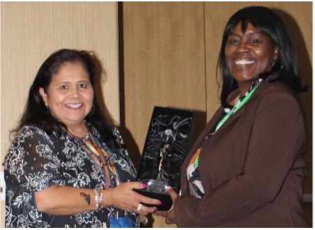 woman handing award to another woman