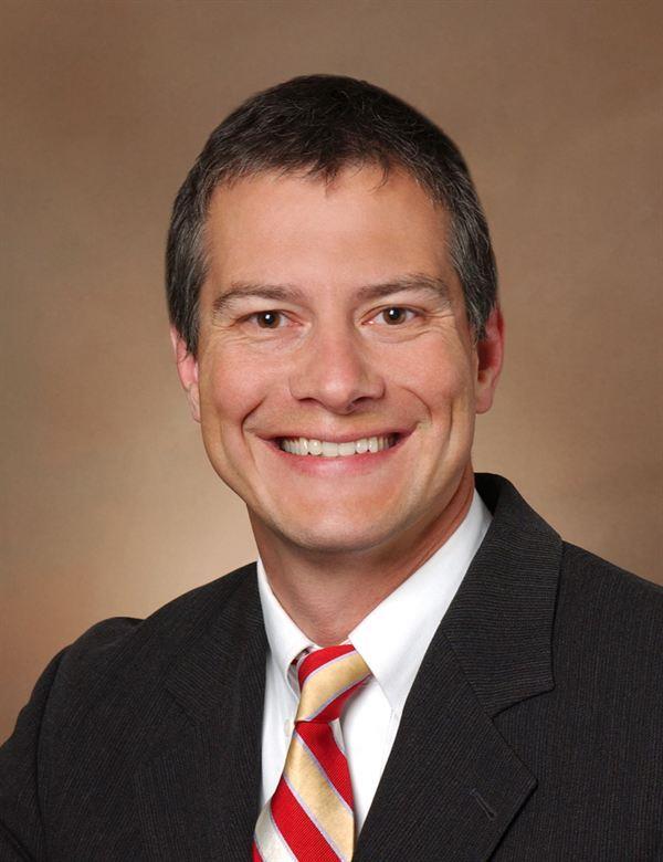 Man with black blazer and gold and red tie