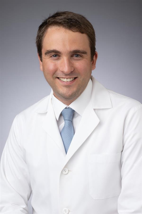 brunette man in white coat and blue tie