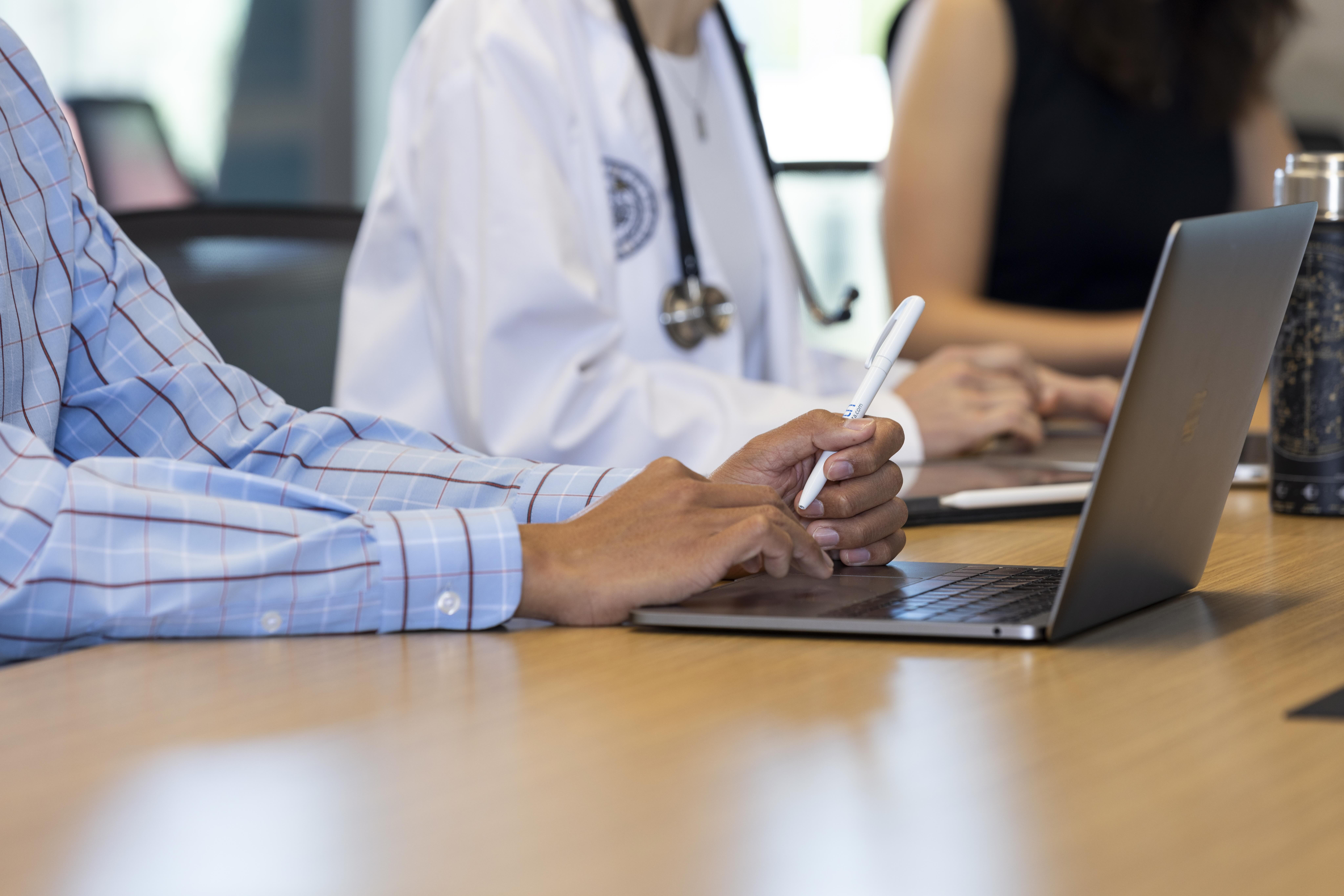 Two doctors type on a laptop