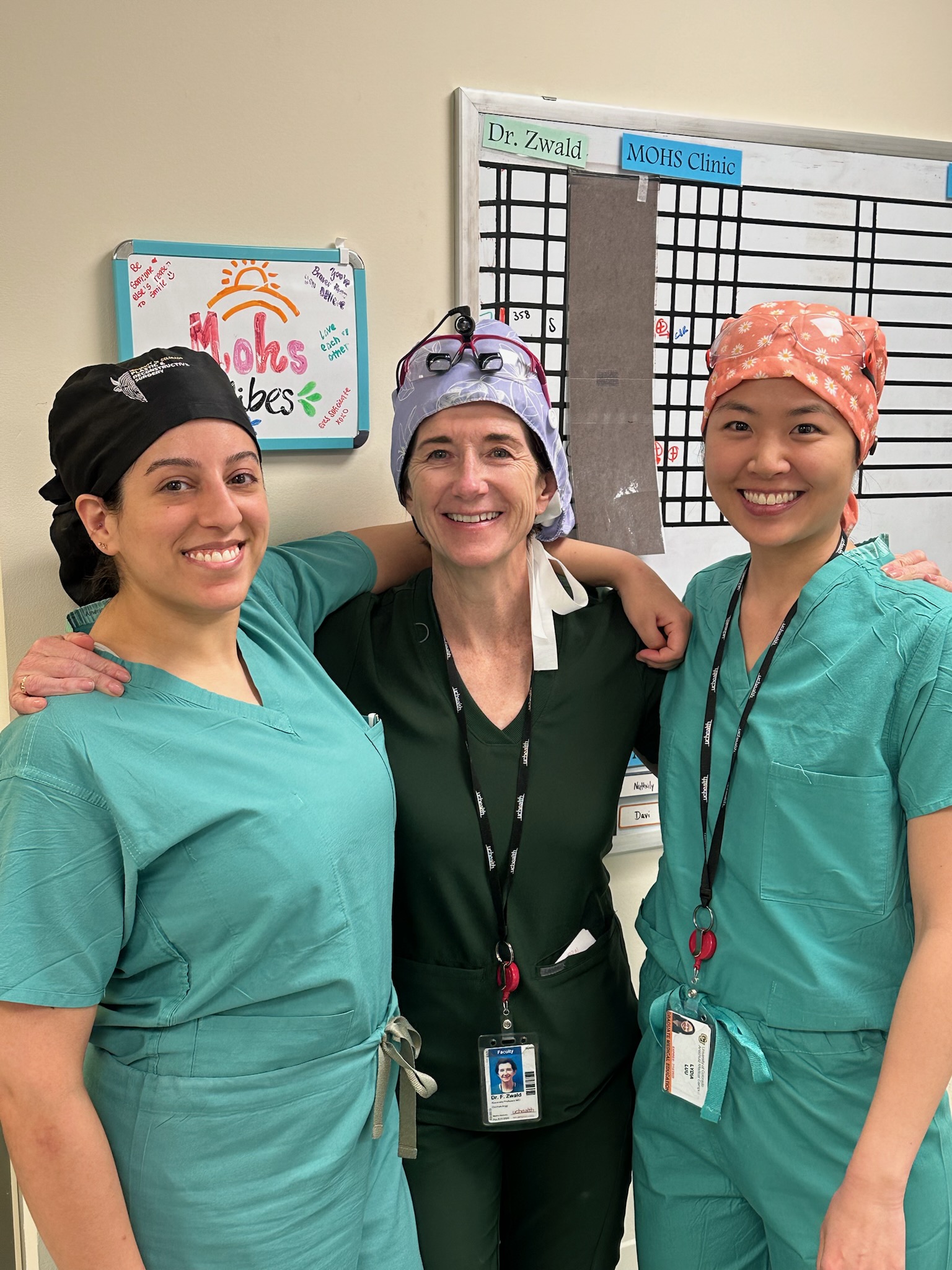 Dr. Orfahli, Dr. Zwald, and Dr. Luu standing in green surgical scrubs and smiling.