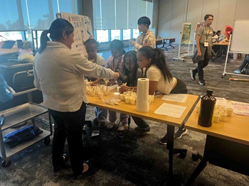 Photooftablewithyouthscienceactivitywithvolunteersandstudents
