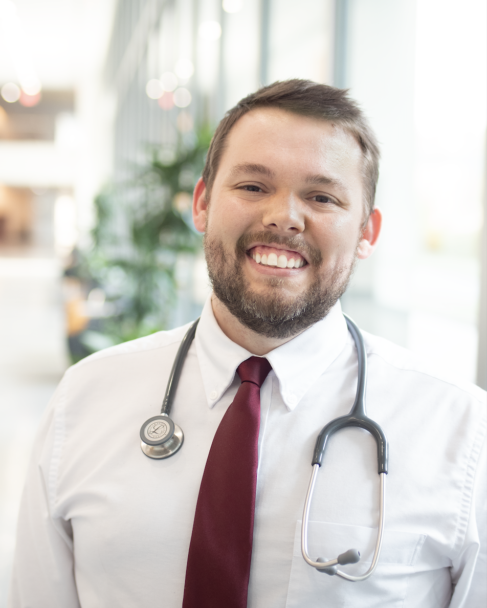 a person smiling with a white button down with a red tie