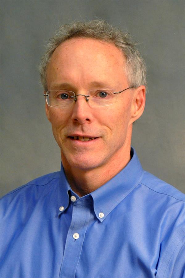 man smiling with a blue button down for a headshot