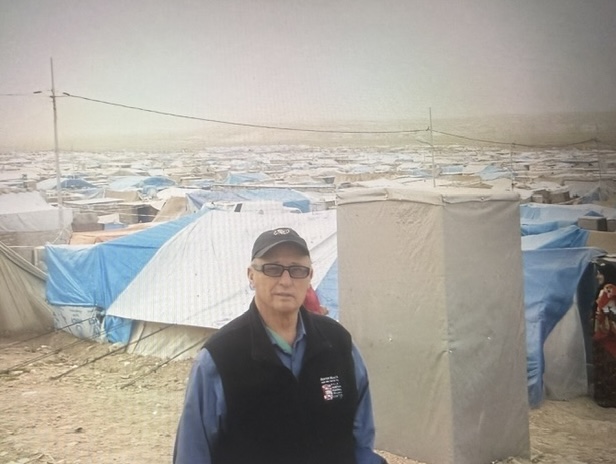 Bolles standing in front of a Syrian refugee camp.