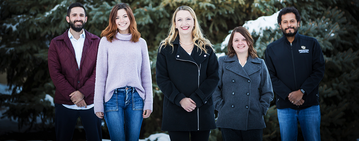 Alexander group photo in front of snowy evergreen tree