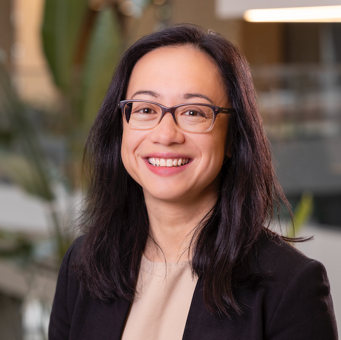 female doctor with glasses, black blazer, and pink blouse
