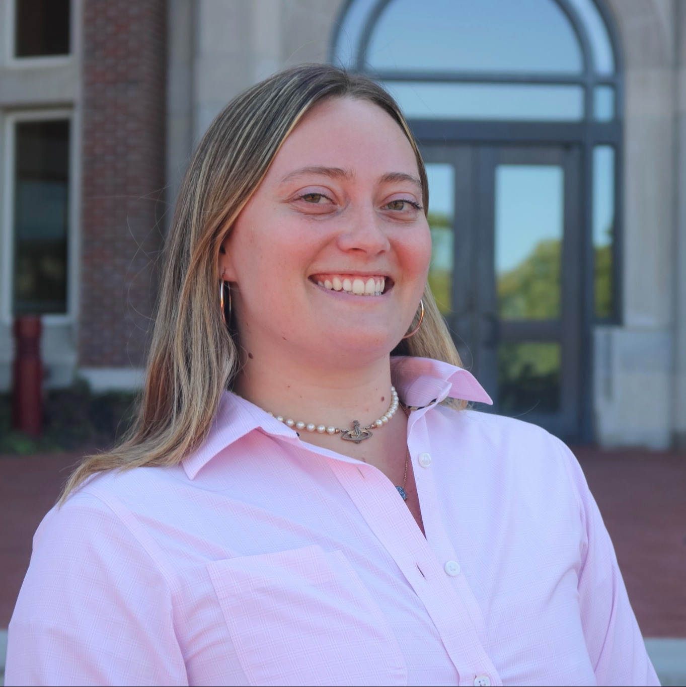 female smiling with a pink long button down shirt