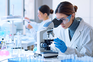 A woman looks into a microscope