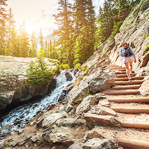 A hiker walks up steps near a stream