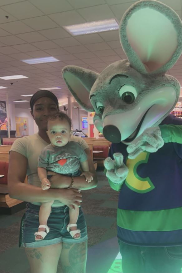 Photo of Dr. Person Jones holding a baby at Chuck-E Cheese.