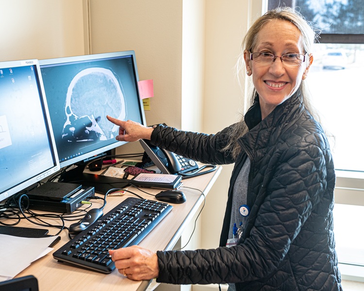 Dr. Heather Baer pointing at a computer screen with an MRI of a human brain.