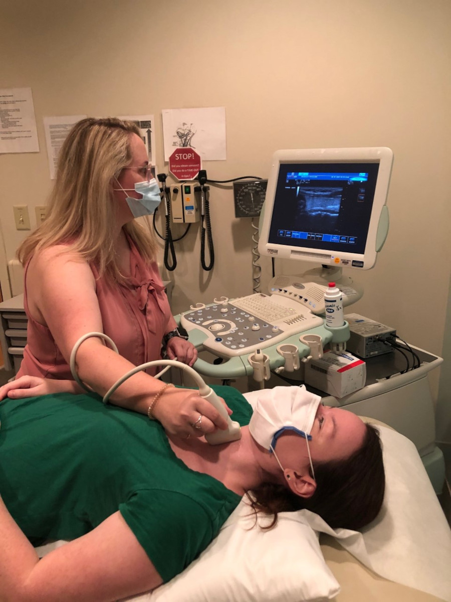 woman using sonogram machine to examine throat
