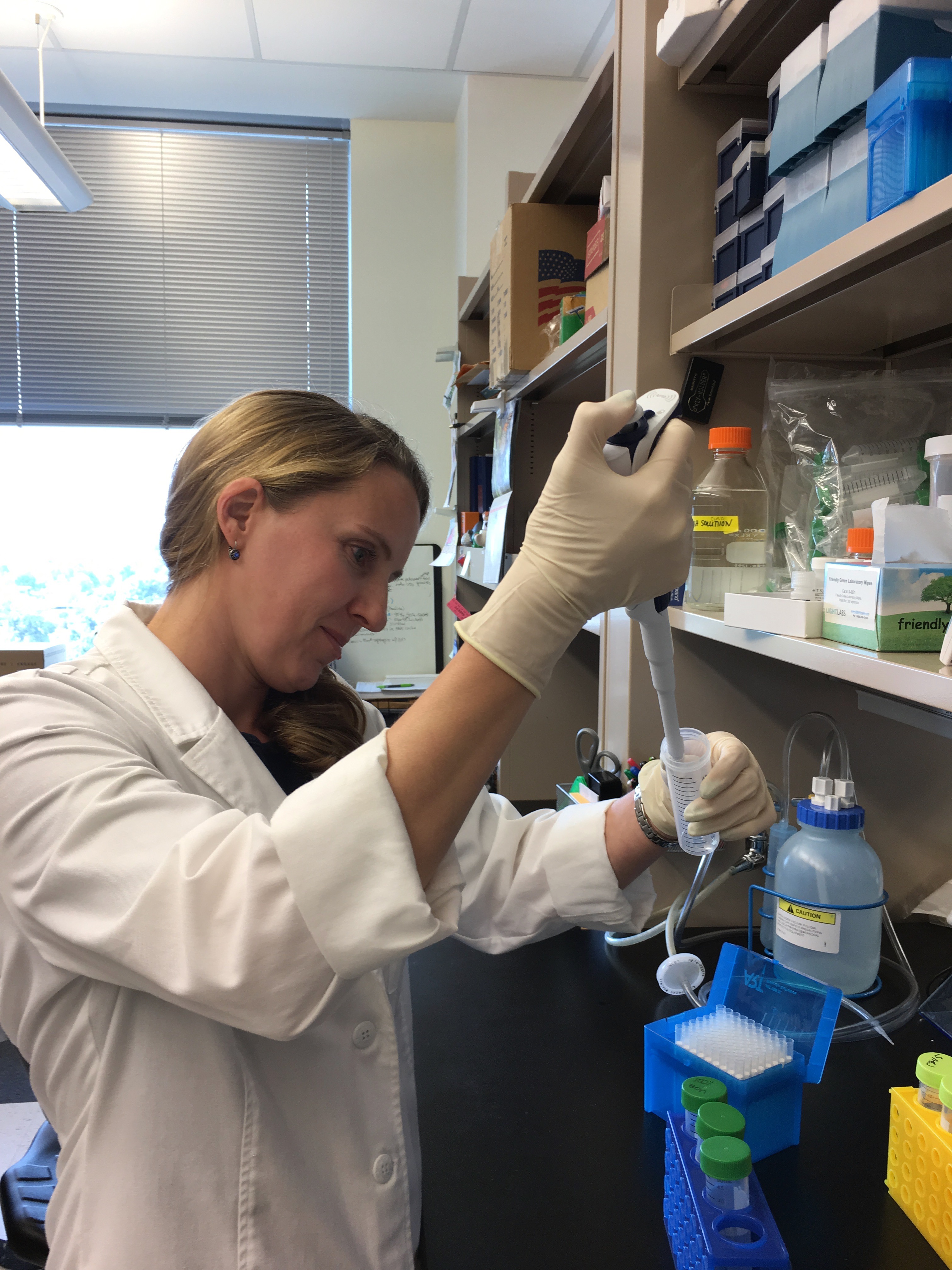 Photo of women in lab coat using a pipette